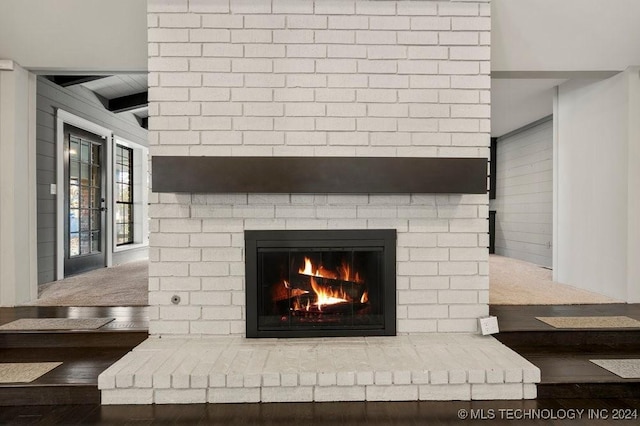 details with beamed ceiling, a fireplace, and wood finished floors