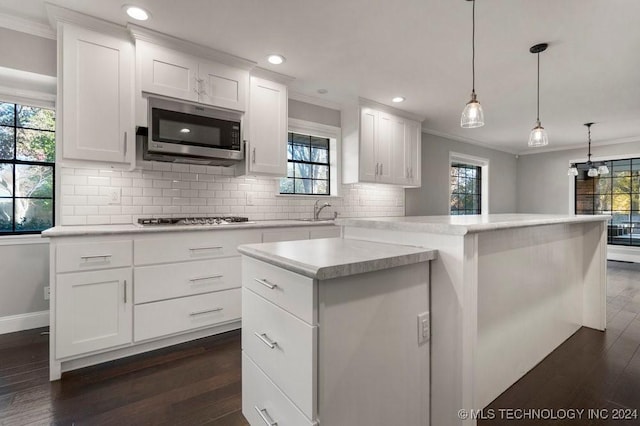 kitchen with dark hardwood / wood-style flooring, stainless steel appliances, a healthy amount of sunlight, white cabinets, and a center island