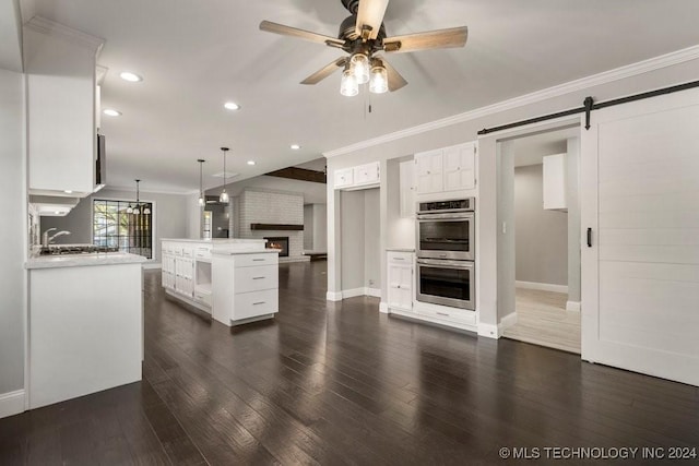 kitchen featuring dark hardwood / wood-style flooring, a center island, stainless steel double oven, and white cabinetry