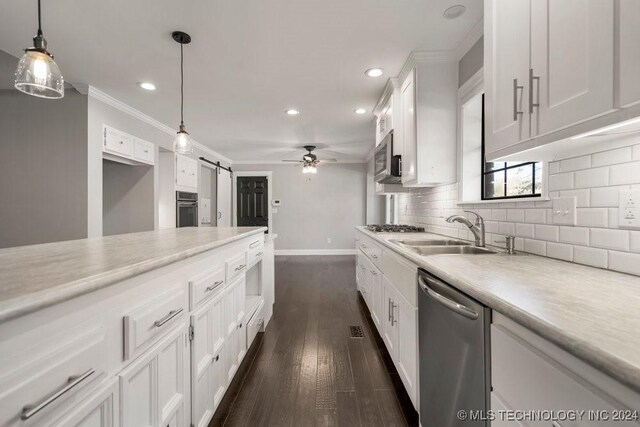 kitchen featuring stainless steel appliances, sink, a barn door, decorative light fixtures, and white cabinets