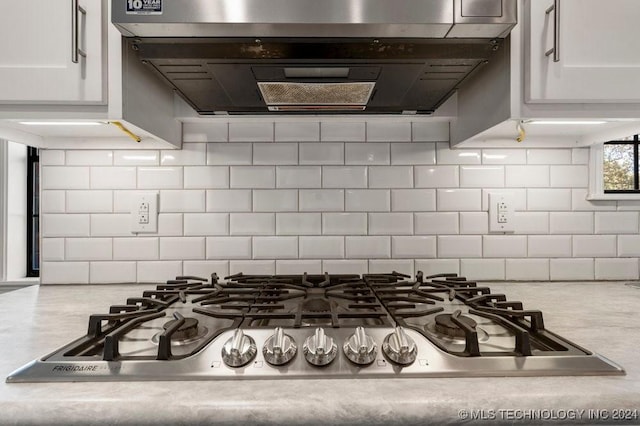 kitchen featuring ventilation hood, white cabinets, backsplash, and stainless steel gas cooktop