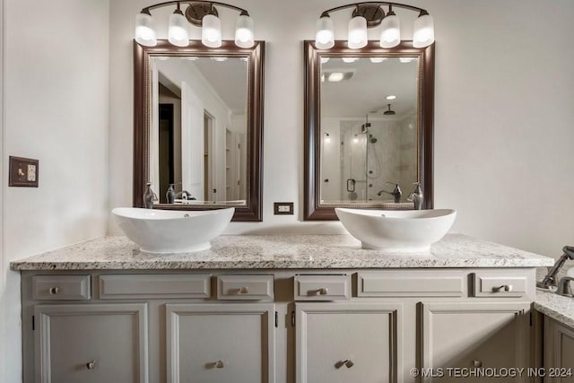 bathroom with a stall shower, a sink, and double vanity