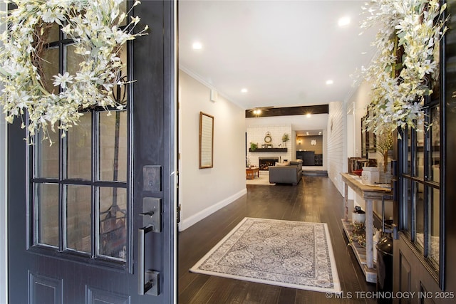 entrance foyer with dark wood-style floors, a fireplace, recessed lighting, ornamental molding, and baseboards