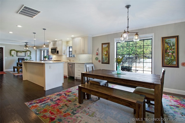 dining area featuring a ceiling fan, visible vents, baseboards, ornamental molding, and dark wood finished floors