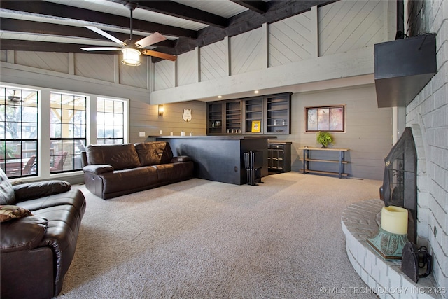 carpeted living area featuring wooden walls, a ceiling fan, bar, beamed ceiling, and high vaulted ceiling