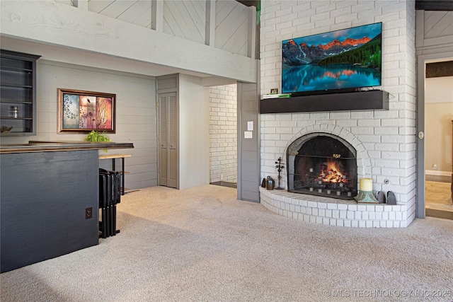 living room with wooden walls, carpet, a fireplace, and a towering ceiling