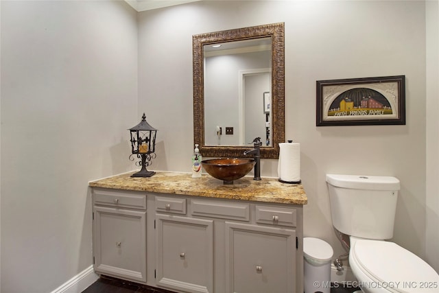 half bath featuring baseboards, vanity, and toilet