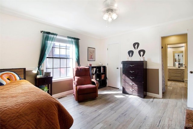 bedroom featuring light wood-style floors, visible vents, crown molding, and baseboards