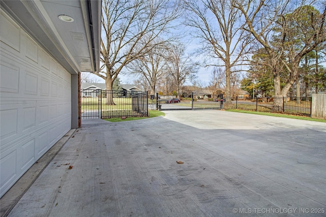 view of patio with a garage, concrete driveway, a gate, and a residential view