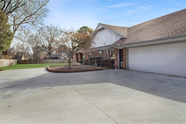 view of property exterior featuring brick siding, fence, concrete driveway, roof with shingles, and board and batten siding