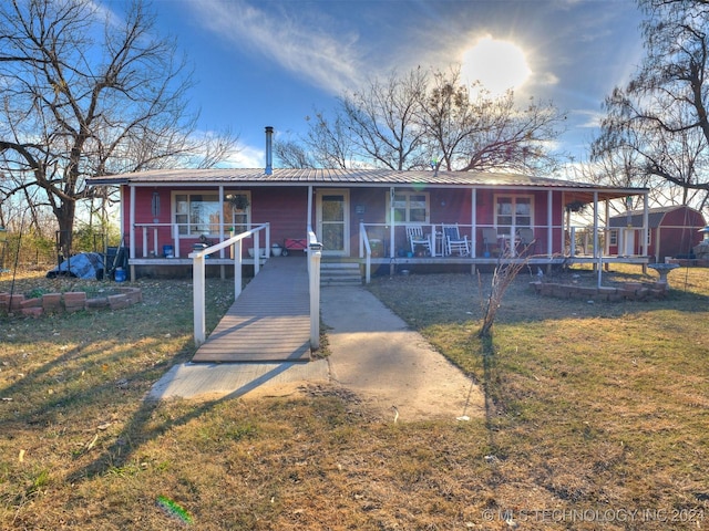 view of front of property featuring a porch, a front yard, and metal roof