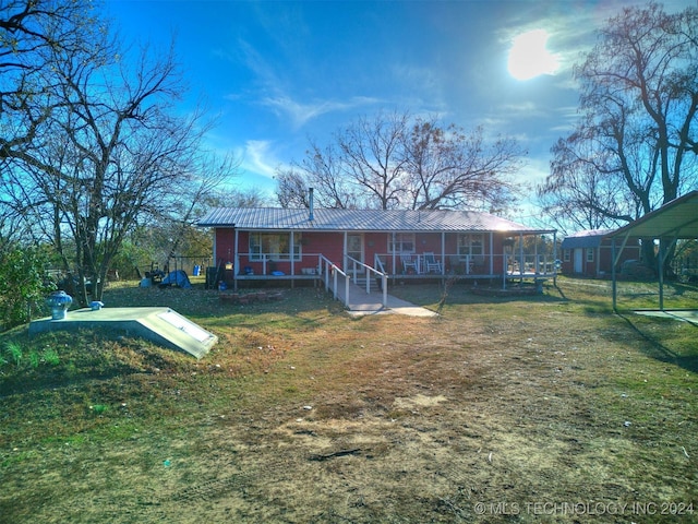 rear view of house with a yard, a sunroom, and metal roof