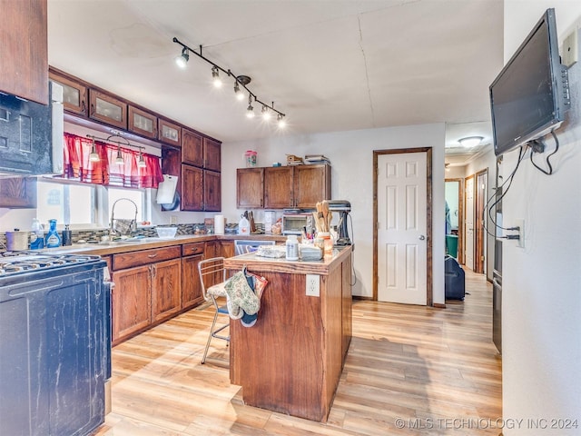 kitchen with light countertops, a kitchen island, light wood finished floors, and a kitchen bar