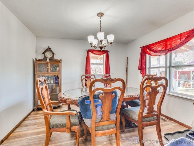 dining space with a chandelier, light wood-style floors, and baseboards