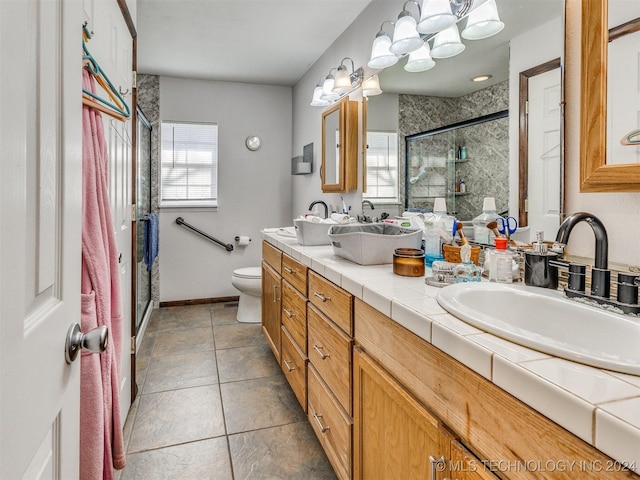 bathroom with double vanity, toilet, a sink, a shower stall, and tile patterned floors