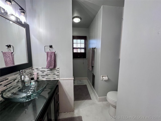 bathroom with tasteful backsplash, vanity, and toilet