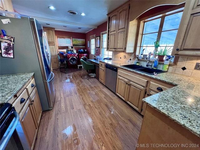 kitchen with appliances with stainless steel finishes, light wood-type flooring, tasteful backsplash, and a healthy amount of sunlight