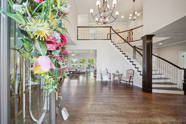 entryway with crown molding, dark wood-type flooring, ceiling fan, and ornate columns