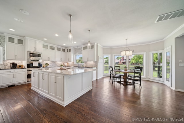 kitchen featuring white cabinetry, stainless steel microwave, ornamental molding, a kitchen island, and pendant lighting