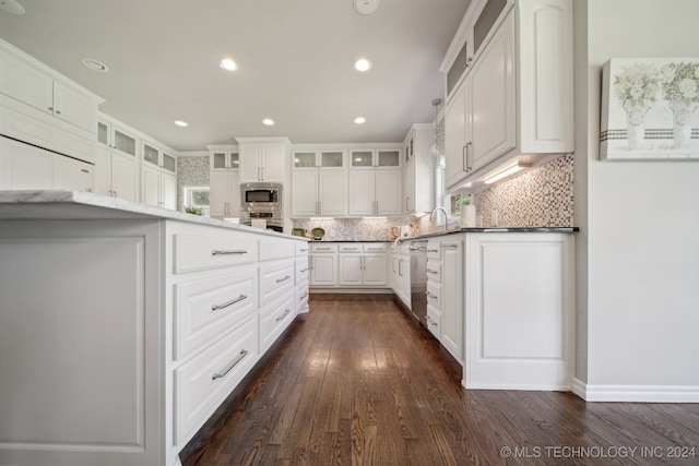 kitchen with tasteful backsplash, appliances with stainless steel finishes, dark wood-type flooring, and white cabinets