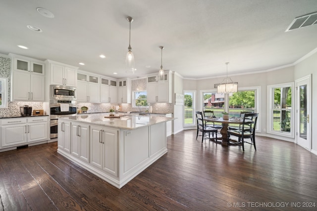 kitchen with a center island, hanging light fixtures, stainless steel microwave, dark hardwood / wood-style floors, and white cabinets