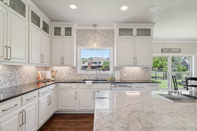 kitchen with sink, crown molding, dark stone countertops, hanging light fixtures, and white cabinets