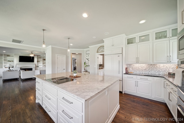 kitchen with hanging light fixtures, black electric stovetop, white cabinets, a kitchen island, and dark stone counters