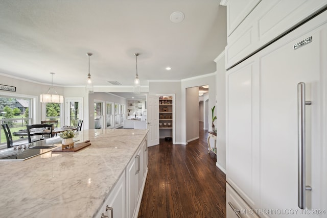 kitchen featuring decorative light fixtures, white cabinetry, dark hardwood / wood-style flooring, crown molding, and light stone countertops