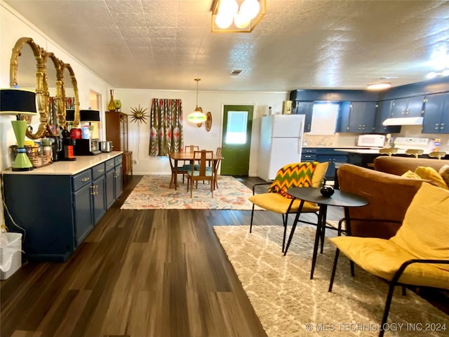 kitchen featuring blue cabinetry, white appliances, dark hardwood / wood-style floors, and hanging light fixtures