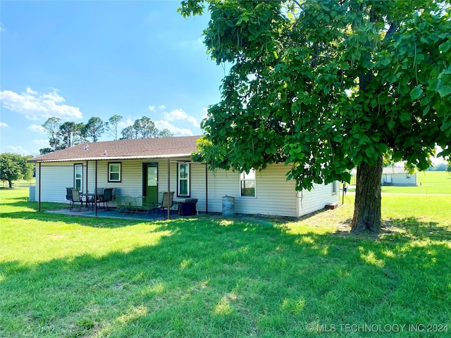 back of property with a yard and a patio