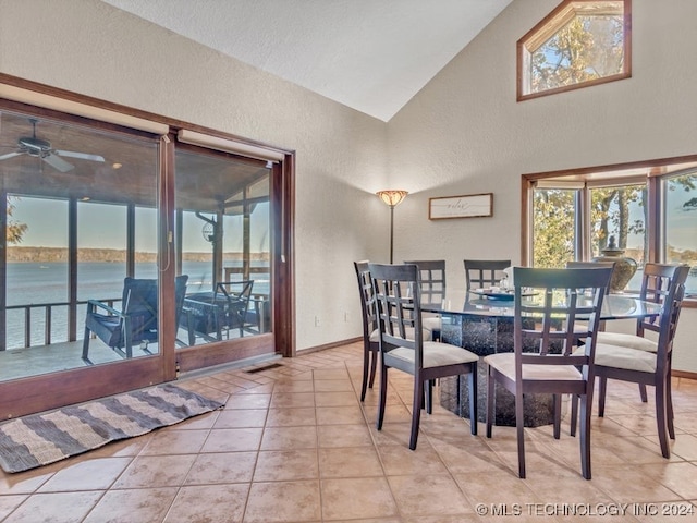 dining room featuring a water view, ceiling fan, light tile patterned floors, and lofted ceiling