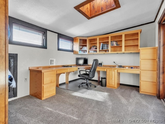 carpeted office featuring a textured ceiling and built in desk