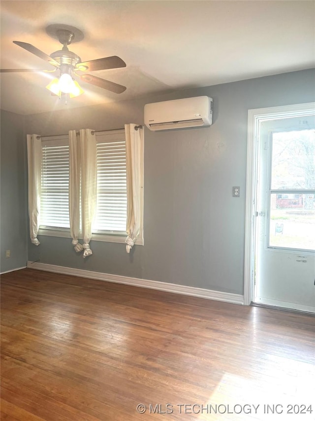 empty room featuring hardwood / wood-style flooring, ceiling fan, and an AC wall unit