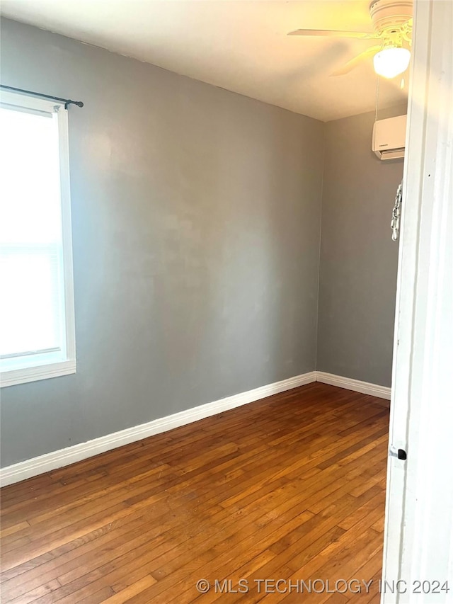 spare room with a wall mounted AC, ceiling fan, and hardwood / wood-style flooring