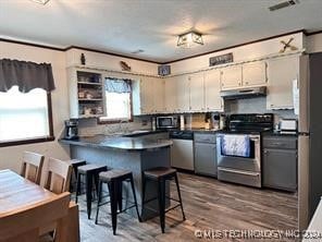 kitchen with a kitchen breakfast bar, kitchen peninsula, hardwood / wood-style flooring, and appliances with stainless steel finishes