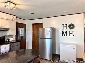 kitchen with stainless steel fridge, black electric range, and white cabinets