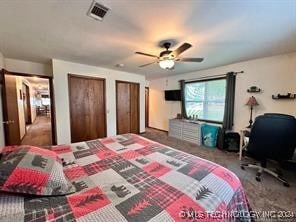 bedroom with dark colored carpet, ceiling fan, and multiple closets