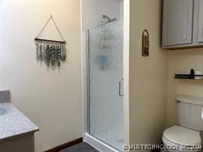 bathroom featuring vanity, toilet, and a shower with door