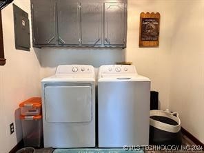 clothes washing area featuring electric panel, cabinets, and independent washer and dryer