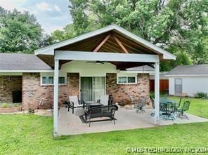 rear view of property featuring a patio area, ceiling fan, an outdoor structure, and a lawn