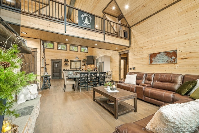 living room featuring wood walls, light hardwood / wood-style floors, wood ceiling, and high vaulted ceiling