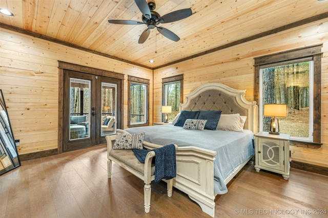 bedroom with hardwood / wood-style floors, ceiling fan, and wooden walls