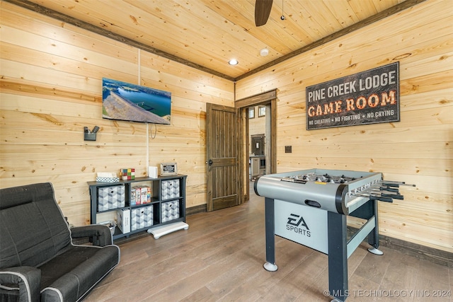 rec room featuring ceiling fan, wood walls, wood-type flooring, and wooden ceiling