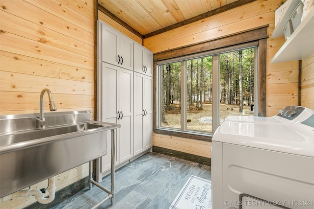 laundry room with cabinets, wood ceiling, wooden walls, sink, and washer and dryer