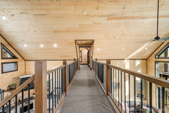 hall with wooden walls, carpet, wood ceiling, and lofted ceiling