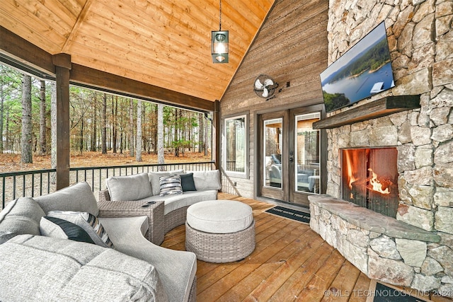 sunroom / solarium featuring wooden ceiling, a healthy amount of sunlight, an outdoor stone fireplace, and lofted ceiling