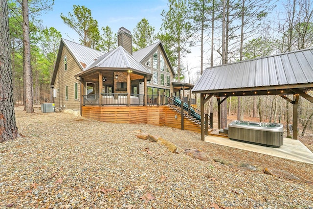 exterior space with central AC unit, a porch, and a hot tub