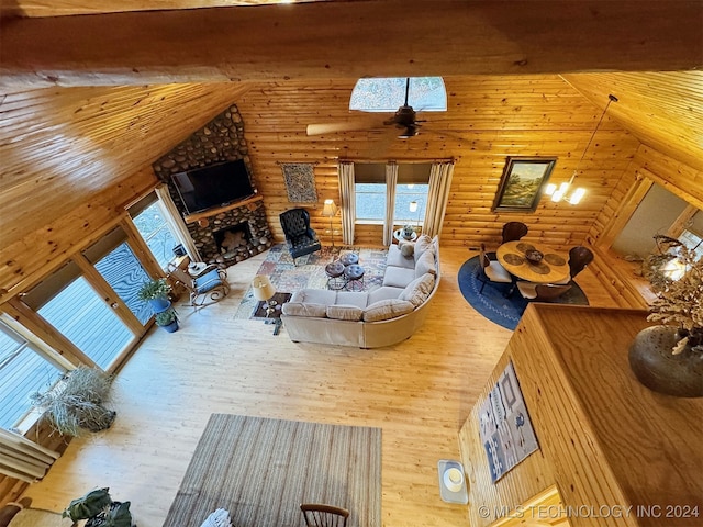 unfurnished living room featuring rustic walls, ceiling fan, high vaulted ceiling, a fireplace, and hardwood / wood-style flooring