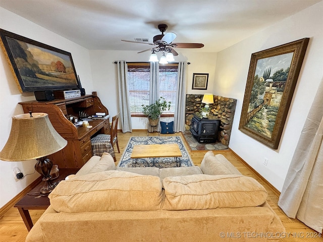 living room featuring light hardwood / wood-style flooring, a wood stove, and ceiling fan