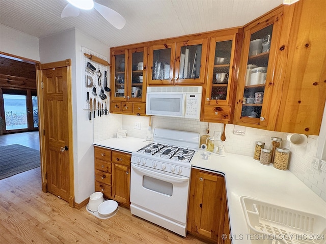 kitchen with light wood-type flooring, white appliances, ceiling fan, and backsplash